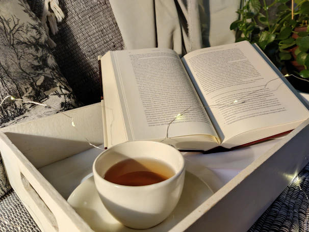 A cozy workspace with an open e-book on Ayurveda and a cup of herbal tea beside it.