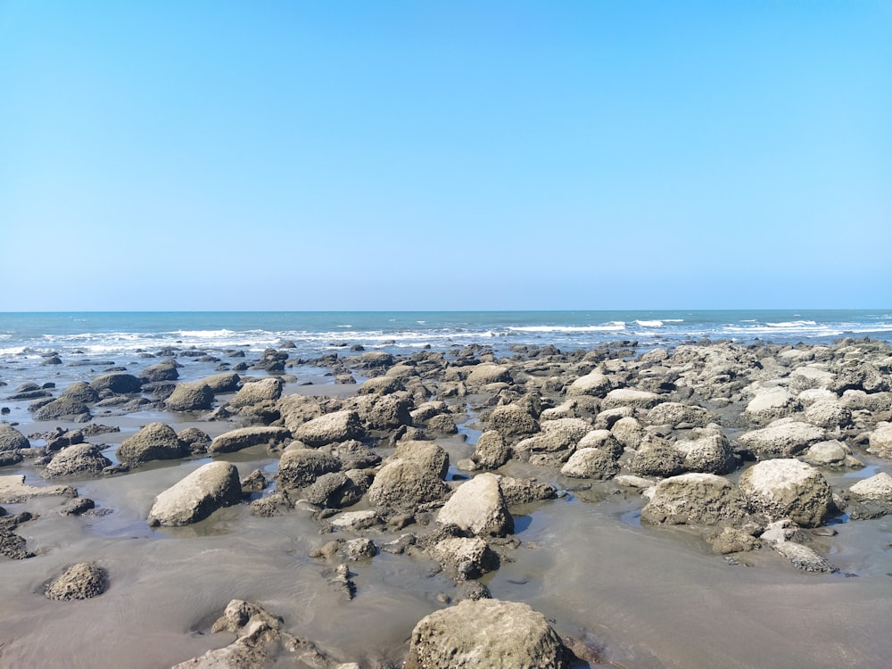 a beach with rocks and water under a blue sky