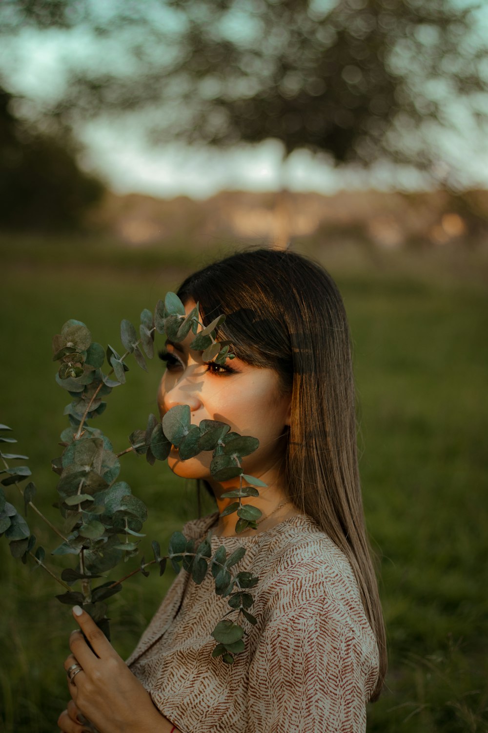 a woman standing in a field with leaves on her face