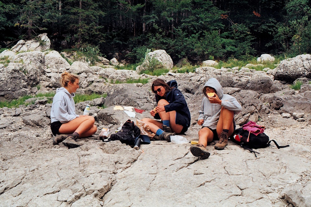a group of people sitting on top of a rocky hillside