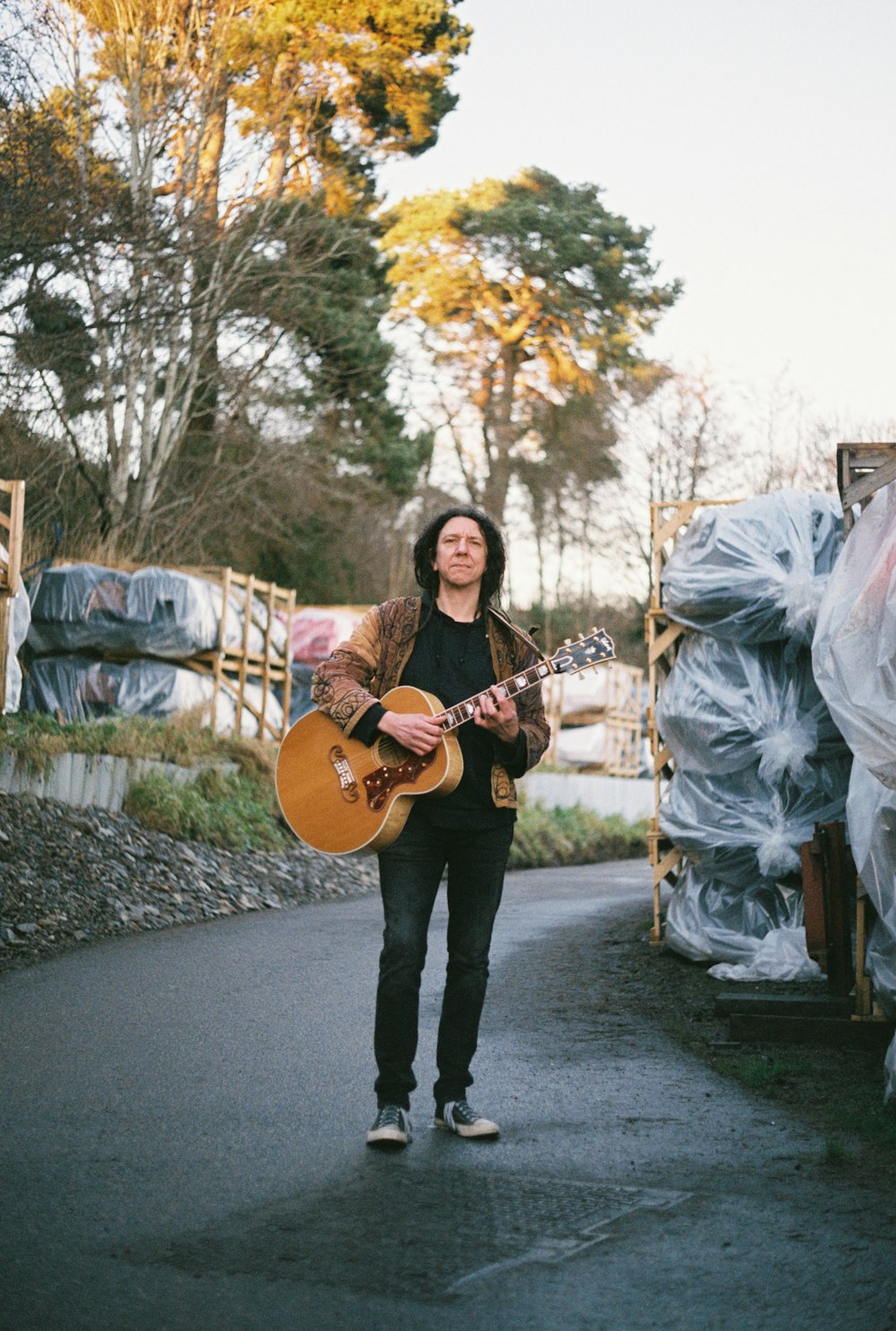 a man holding a guitar walking down a street