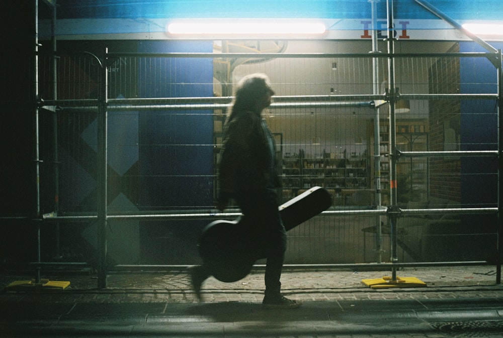 a man walking down a street holding a skateboard