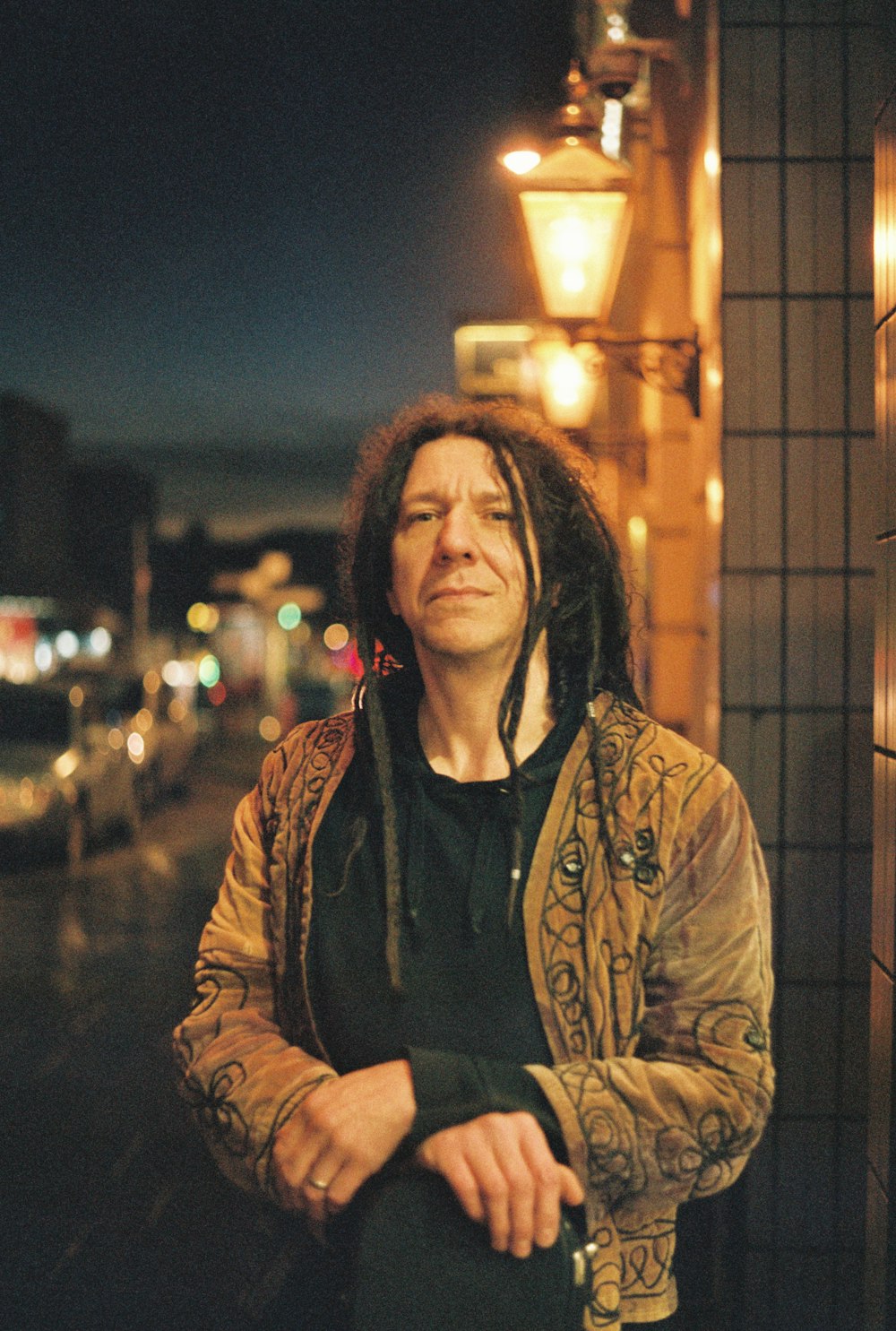 a man with dreadlocks standing in front of a building