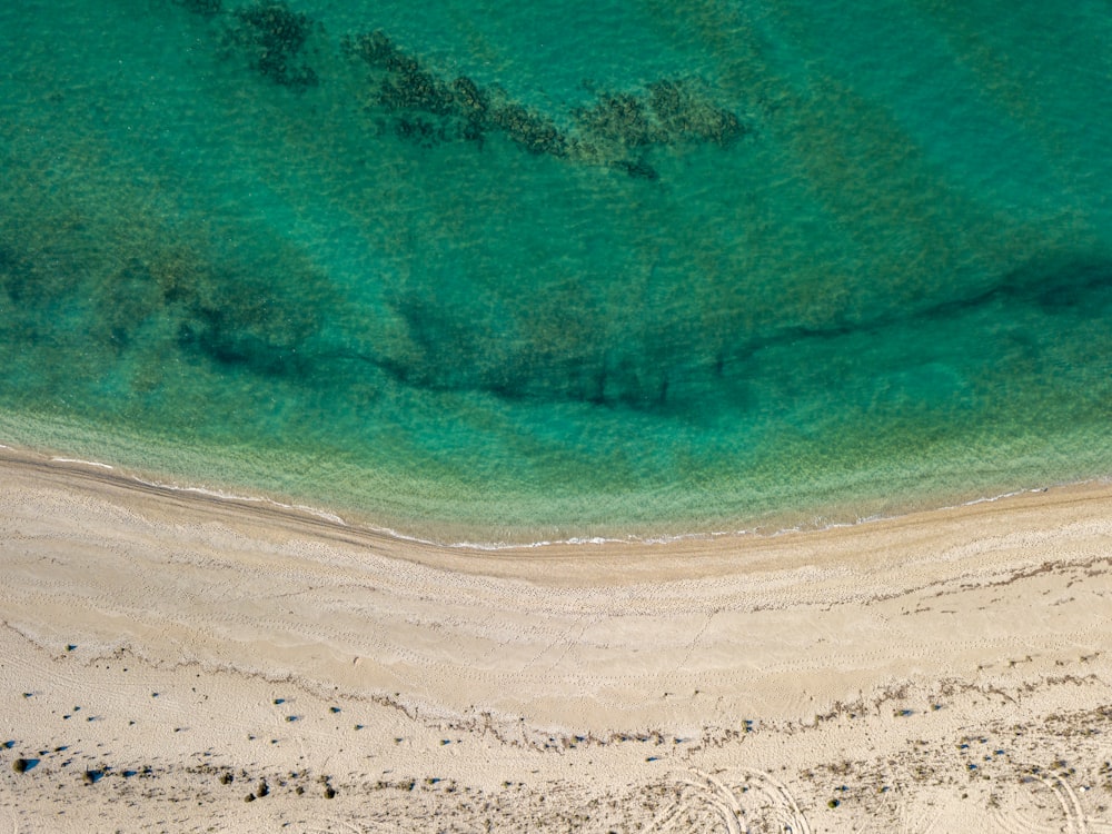 an aerial view of a sandy beach with clear blue water