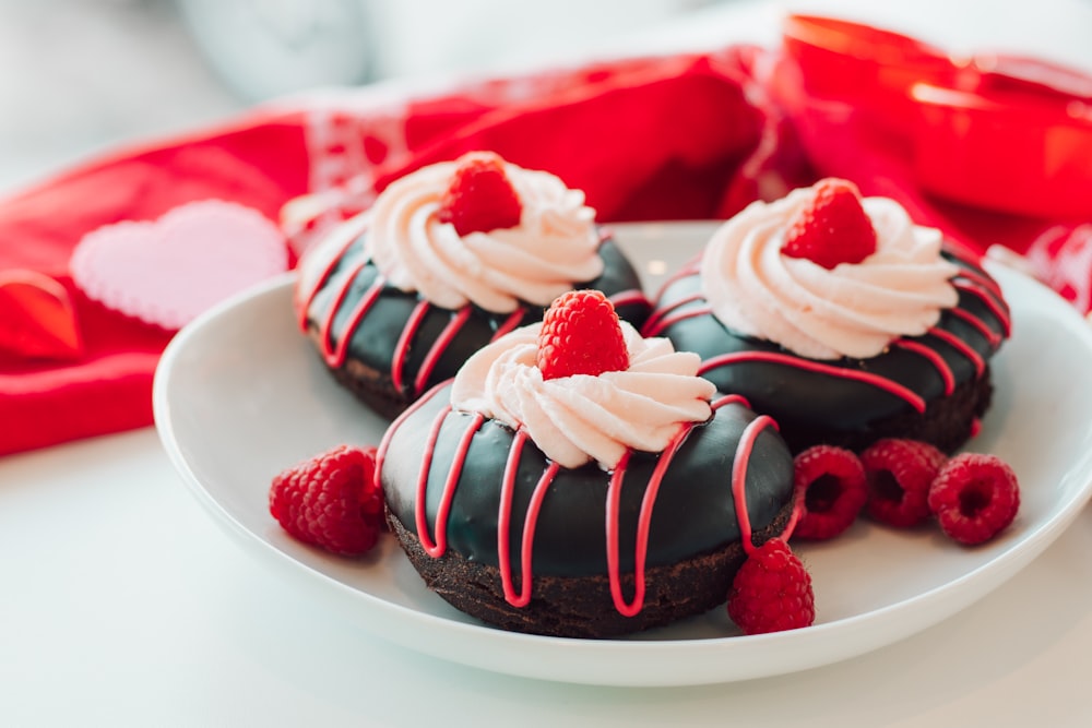 a white plate topped with chocolate covered donuts and raspberries