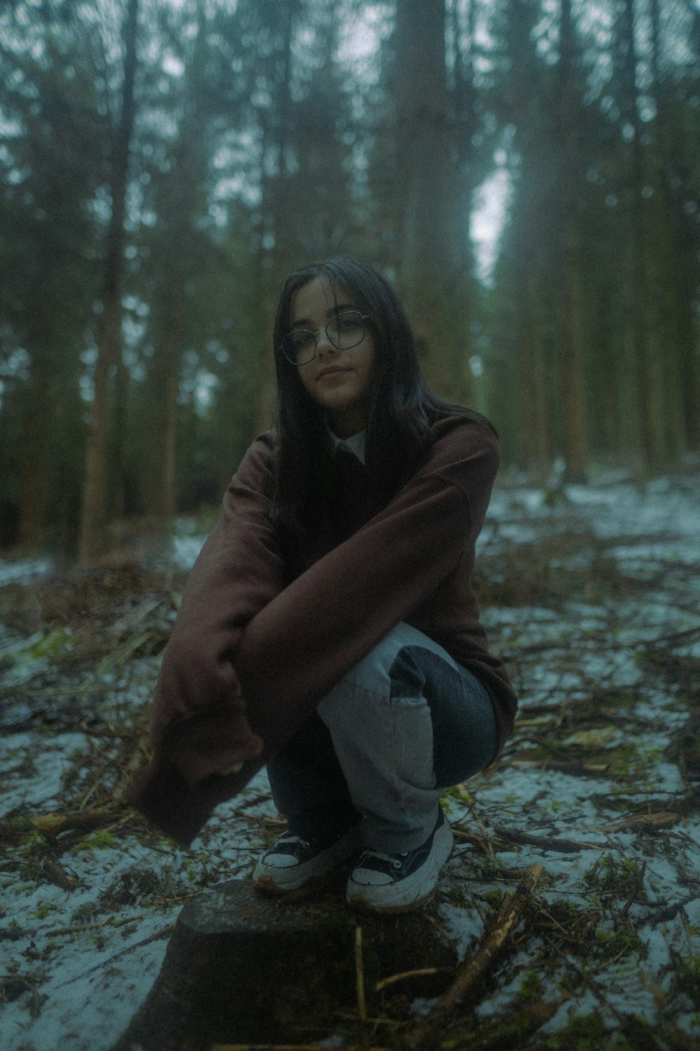 a woman squatting down in the woods