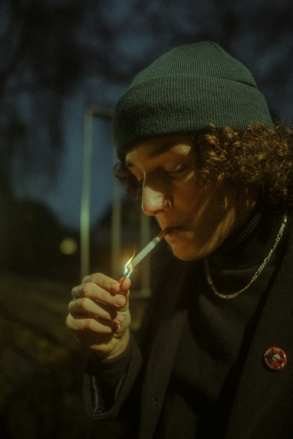 a man in a green hat lights a cigarette