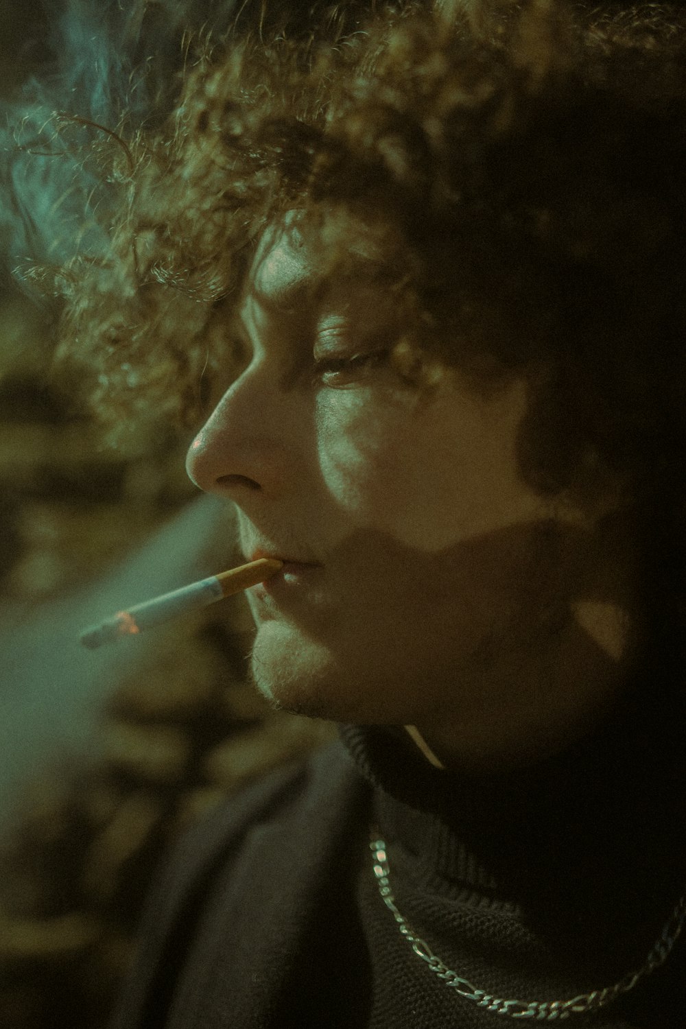 a man with curly hair smoking a cigarette