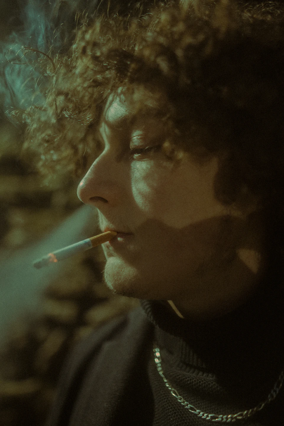 Close-up view of person's face, eyes closed, mouth slightly open while smoking a cigarette
