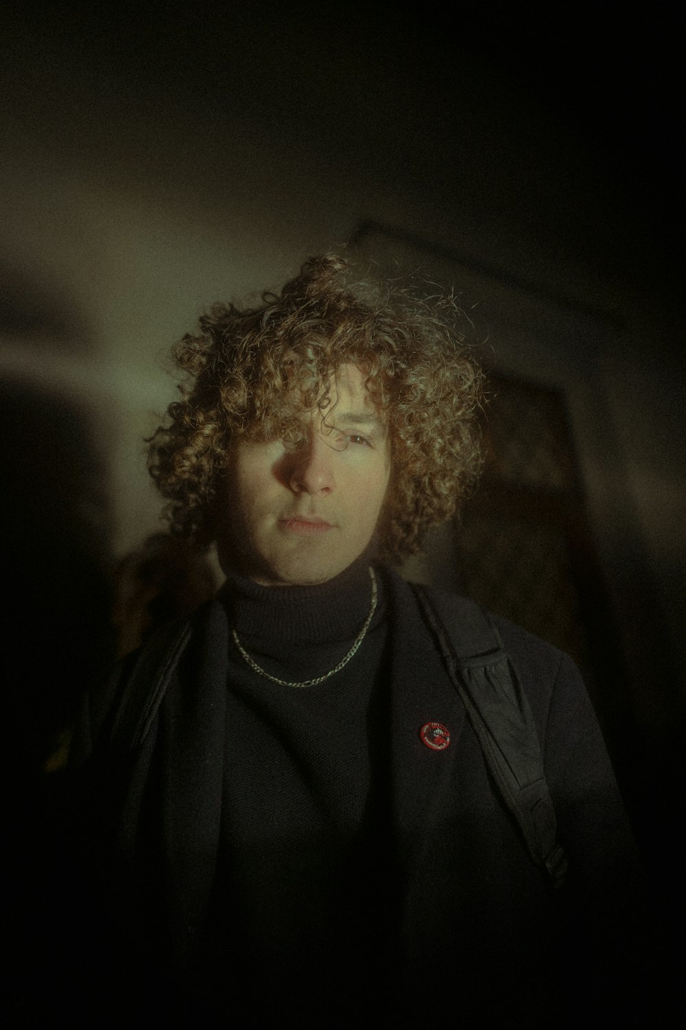 a woman with curly hair standing in a dark room