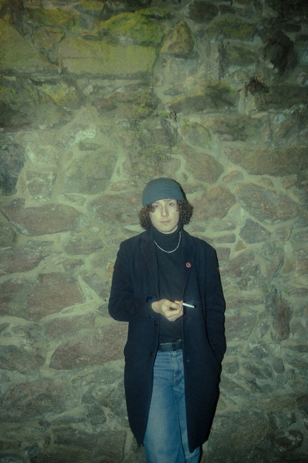 a man standing in front of a stone wall