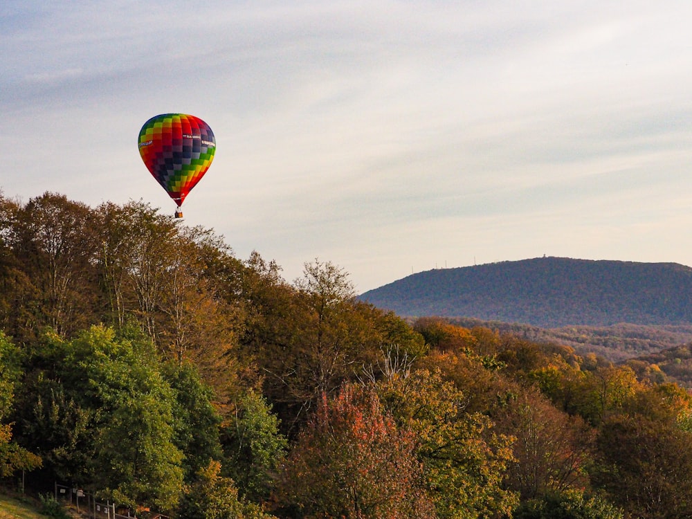 a hot air balloon flying over a lush green hillside