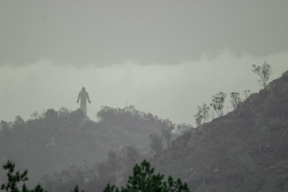 a person standing on top of a hill on a foggy day