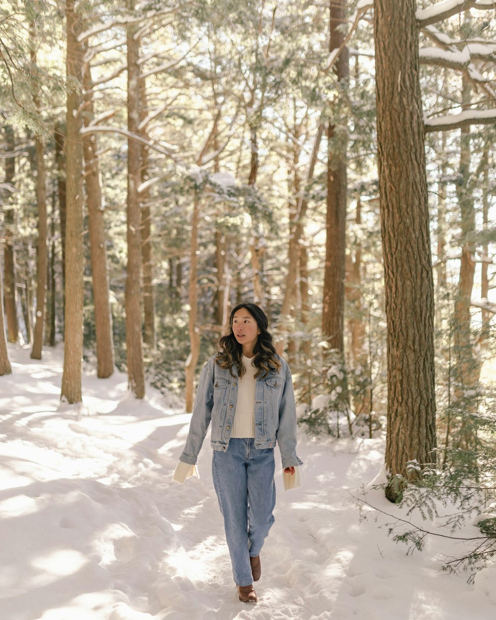 a woman walking through the snow in the woods