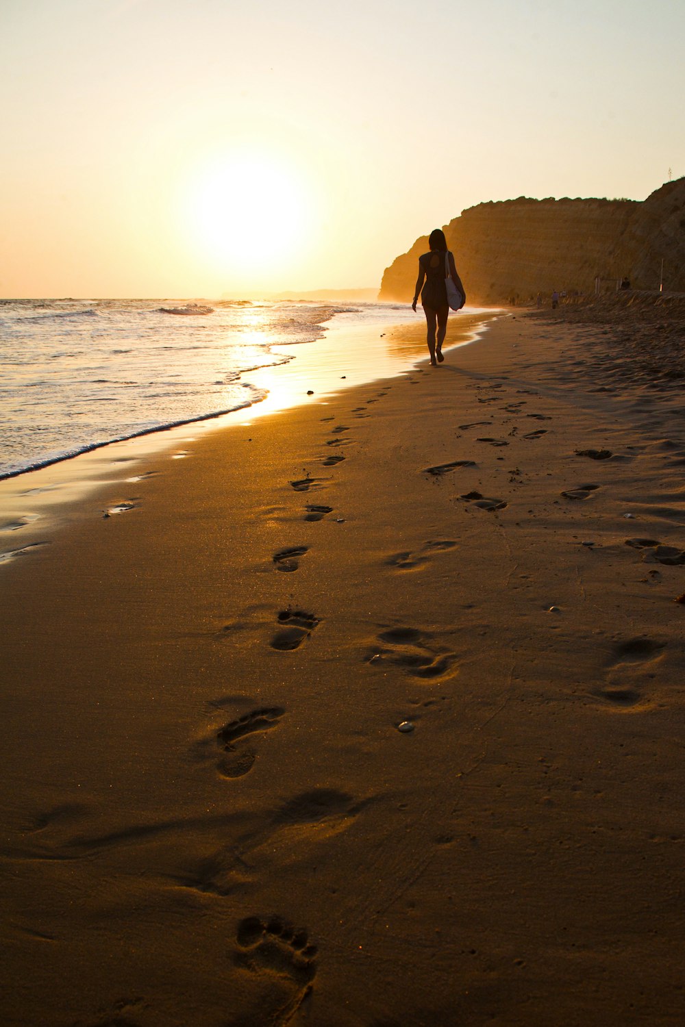 a person walking along a beach with footprints in the sand