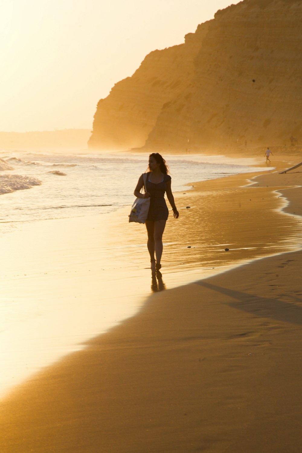 a woman walking on the beach with a surfboard