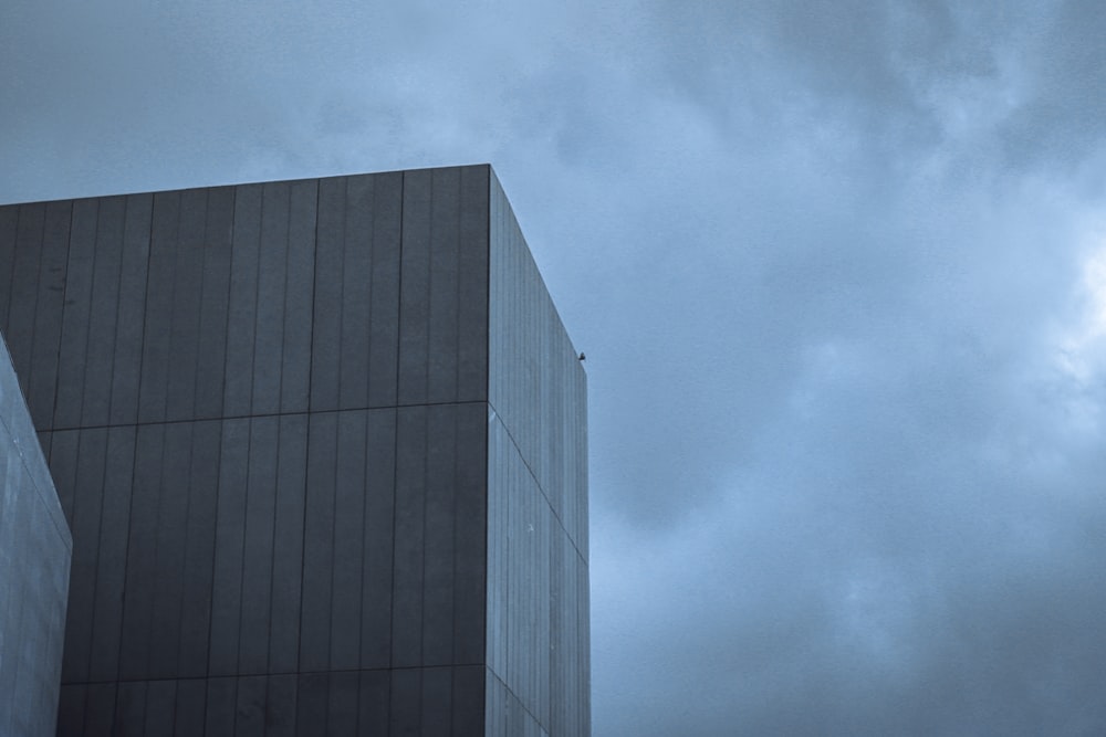 a tall building sitting next to a tall building under a cloudy sky