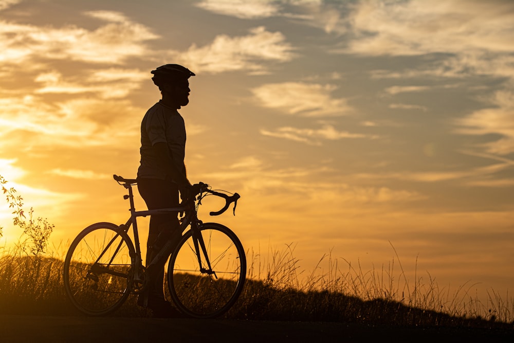 a man standing next to a bike at sunset