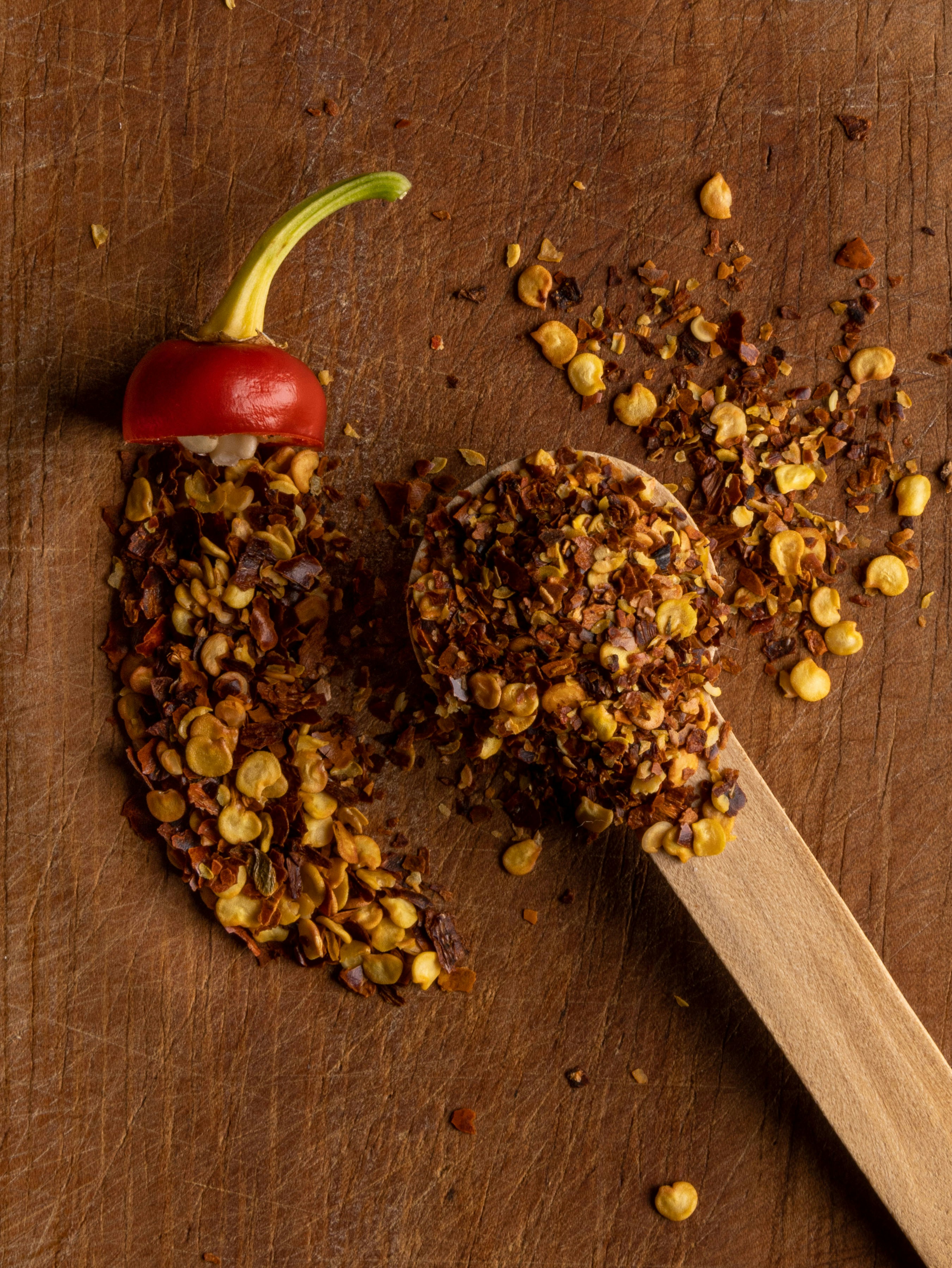 a wooden spoon filled with granola next to a red pepper