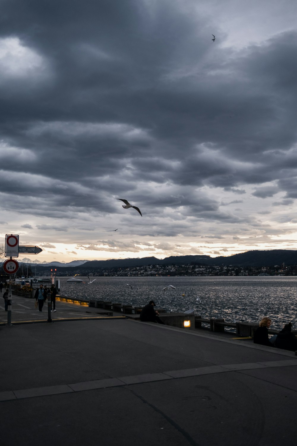 a group of people standing on top of a pier under a cloudy sky