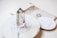 A clear quartz crystal stands upright on a circular, decorative mandala-patterned base. The background includes a soft fabric pouch with a geometric design and a round card with text, adding to the aesthetic appeal.