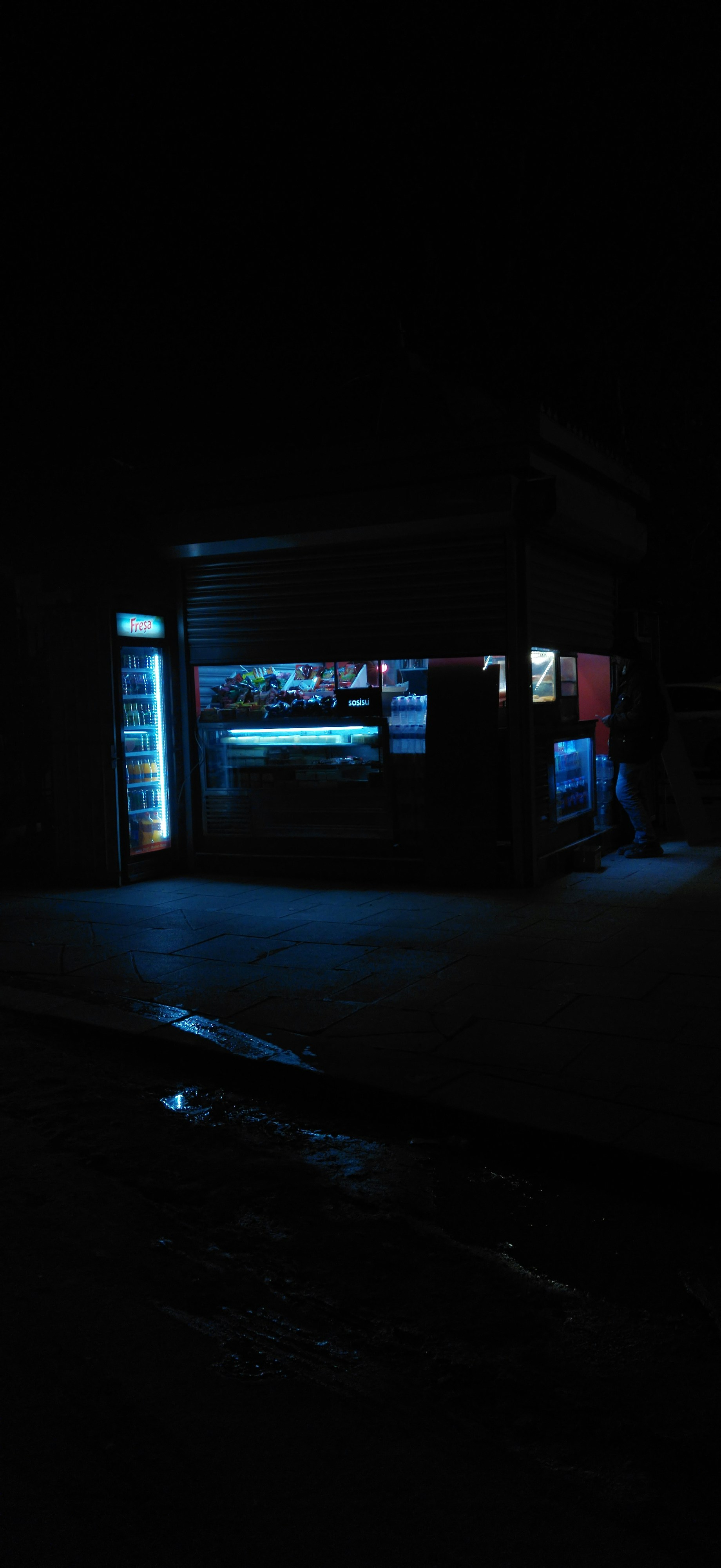 a dark street at night with a store front lit up
