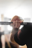 Close-up of hands gripping a horizontal bar with chalk dust in the air.