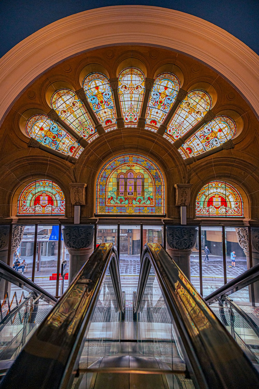 an escalator in a building with stained glass windows