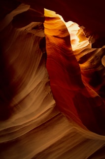 Sunlight beams filtering through the narrow walls of Antelope Canyon, illuminating the red sandstone curves.