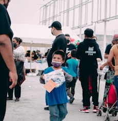 a young boy walking down a street next to a group of people