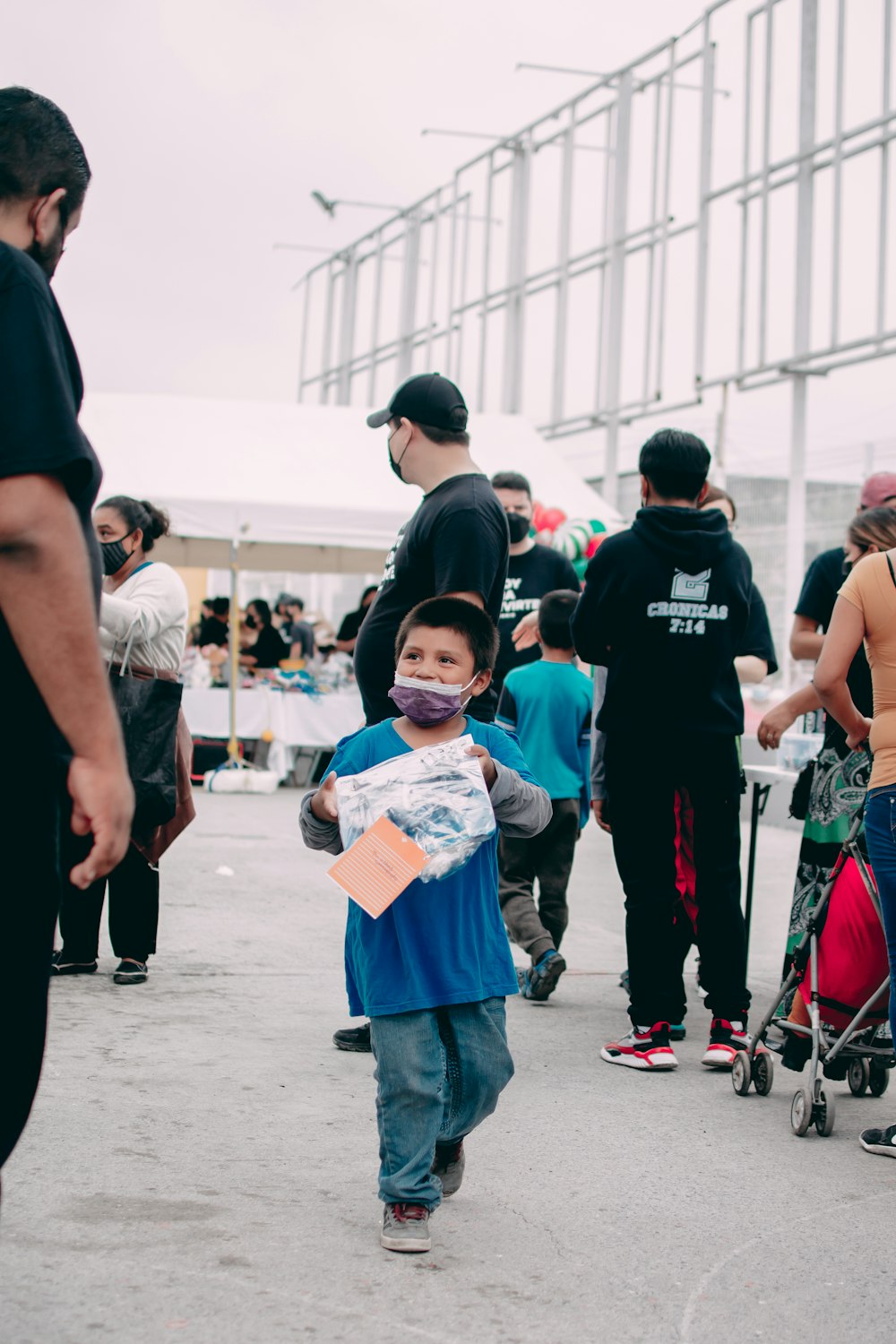 a young boy walking down a street next to a group of people