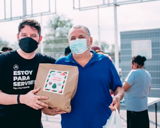 two men wearing masks and holding a bag of food