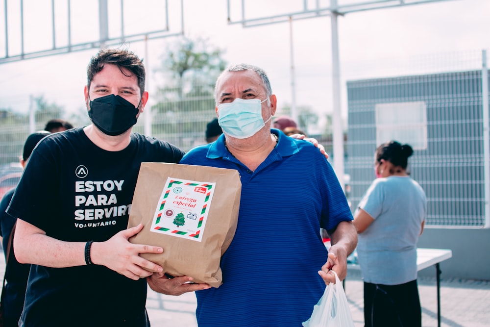 two men wearing masks and holding a bag of food