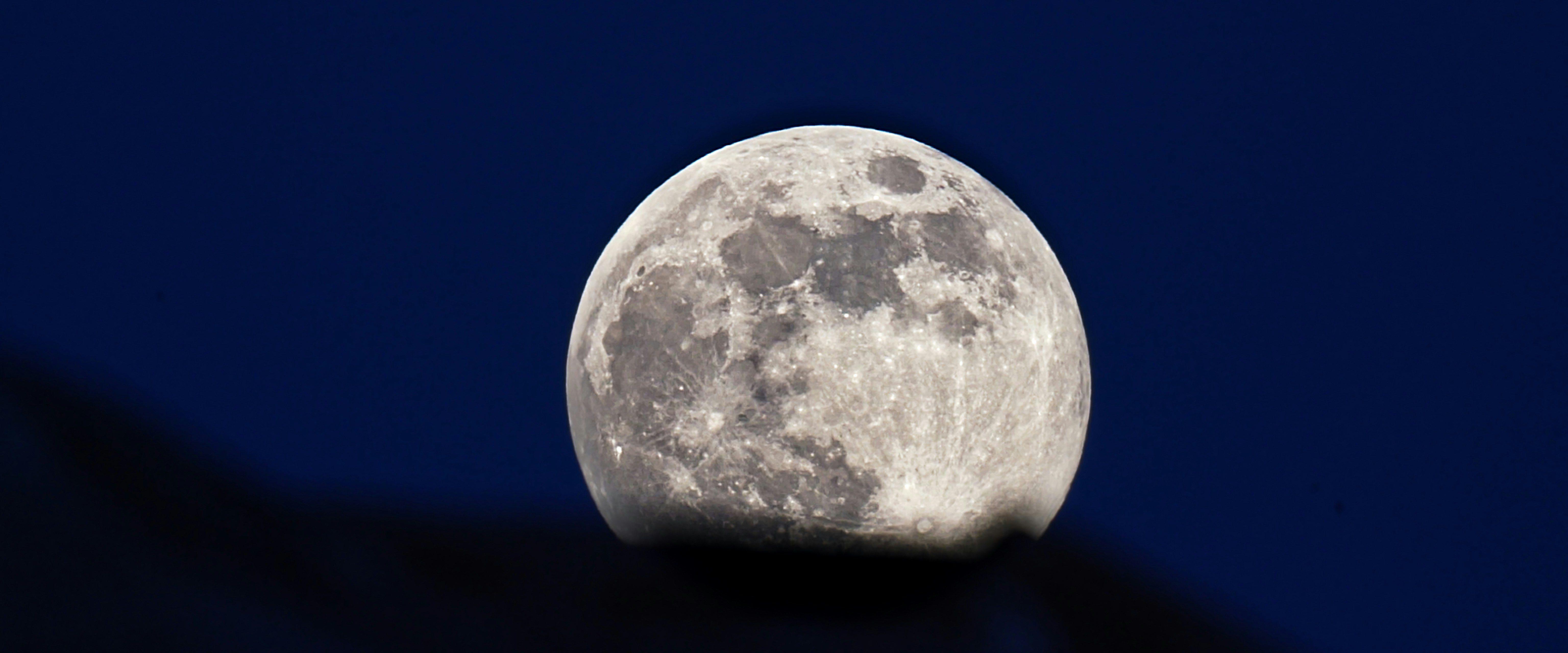 a full moon is seen in the night sky