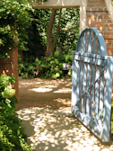 A sunlit garden gate framed by blooming roses and lush greenery.
