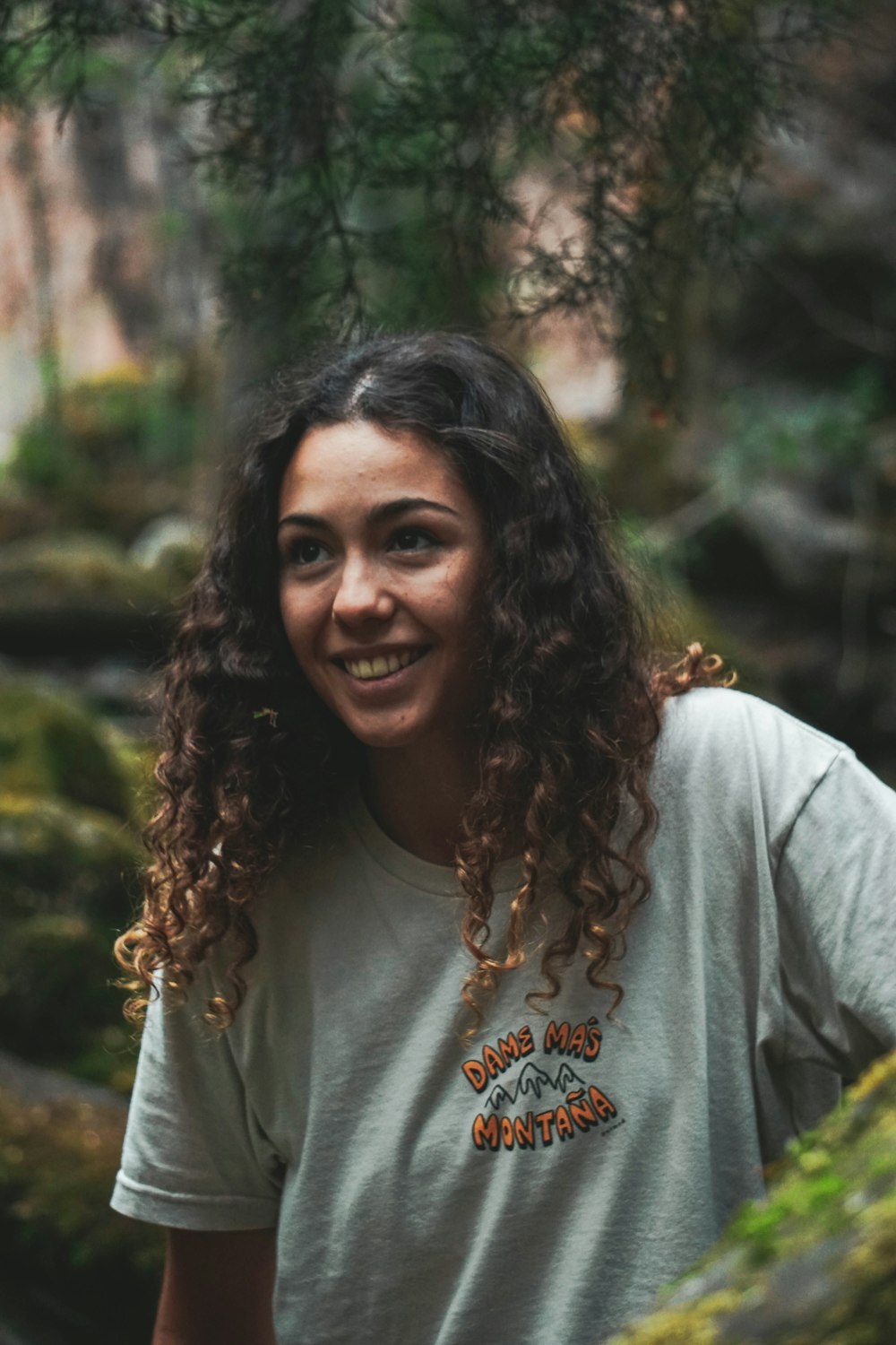 a woman with curly hair standing in a forest