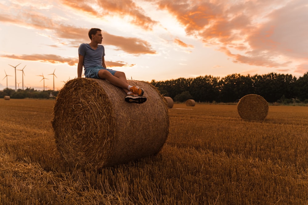 a man sitting on a bale of hay in a field
