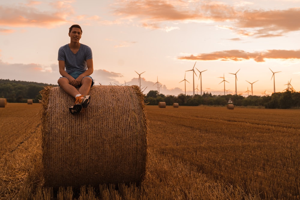 a man sitting on a bale of hay in a field