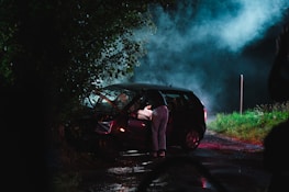 a person standing next to a car with smoke coming out of it