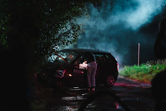 a person standing next to a car with smoke coming out of it