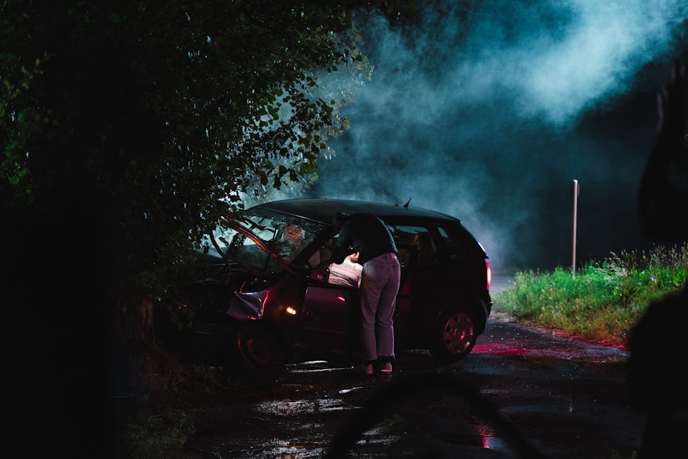a person standing next to a car with smoke coming out of it