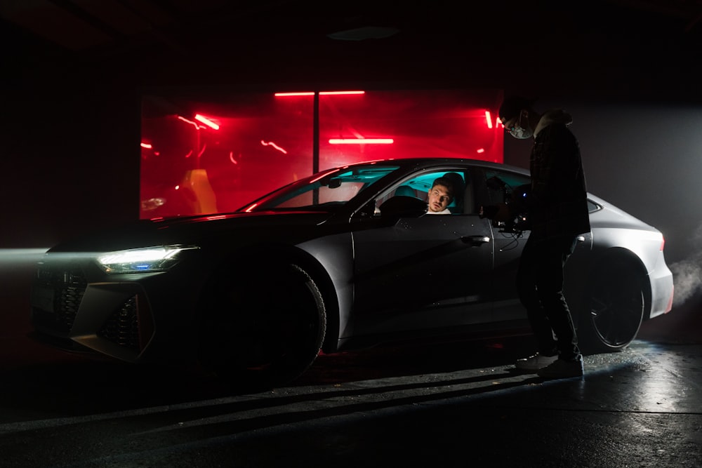 a man standing next to a car in a dark room