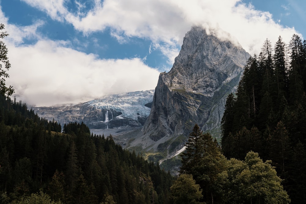 a very tall mountain surrounded by trees and clouds