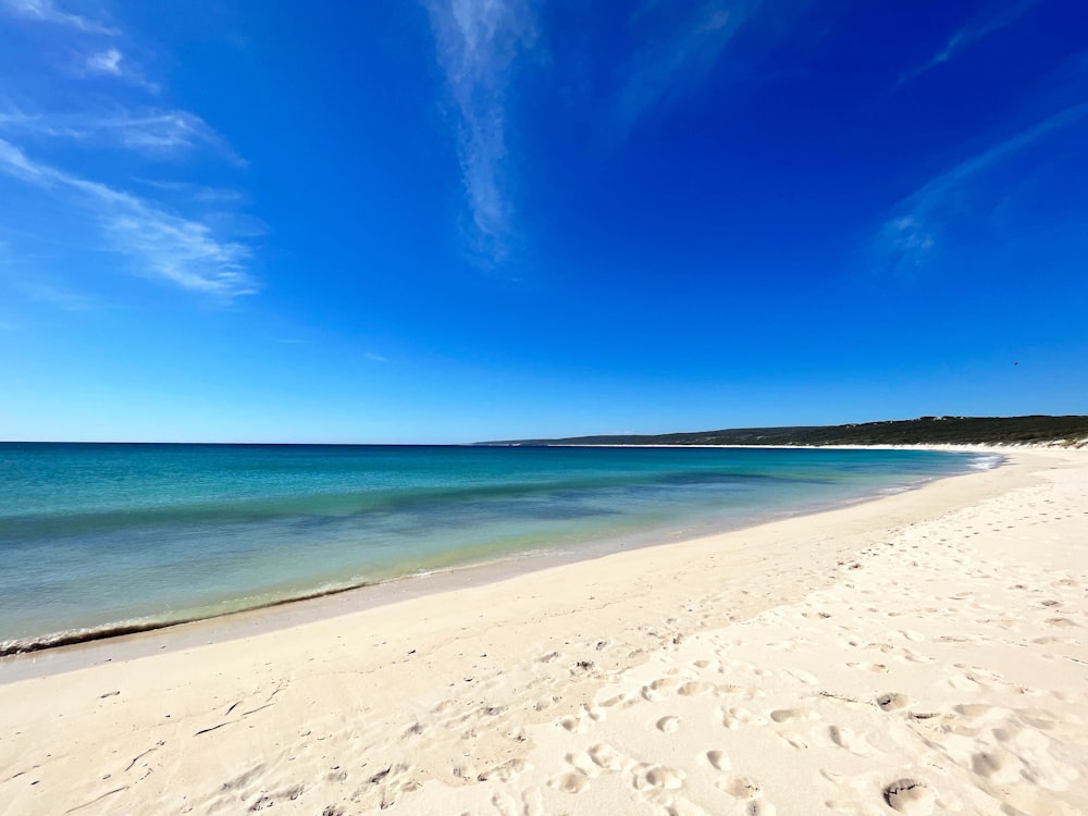 a sandy beach with clear blue water on a sunny day