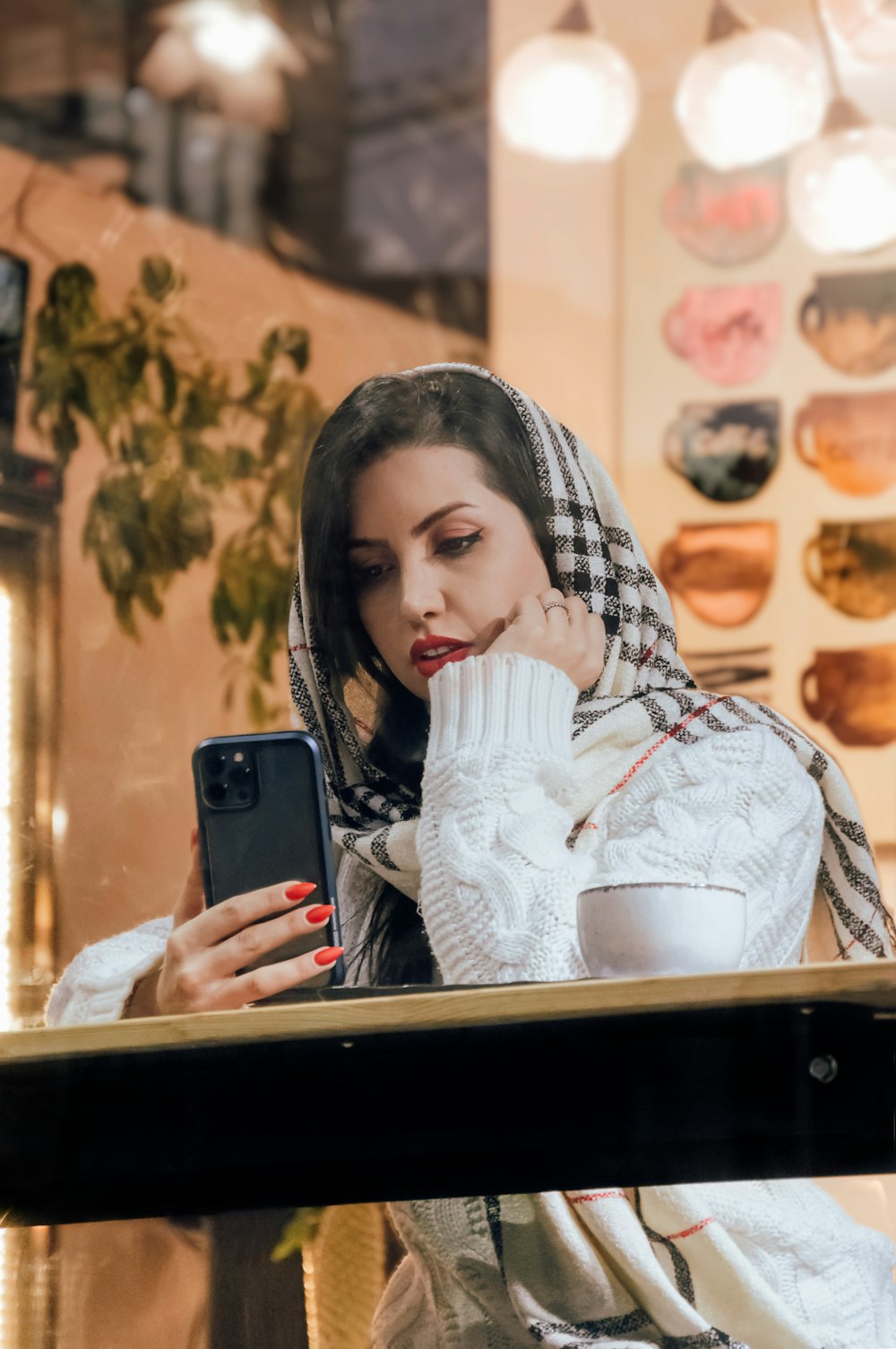 a woman in a scarf is looking at her cell phone
