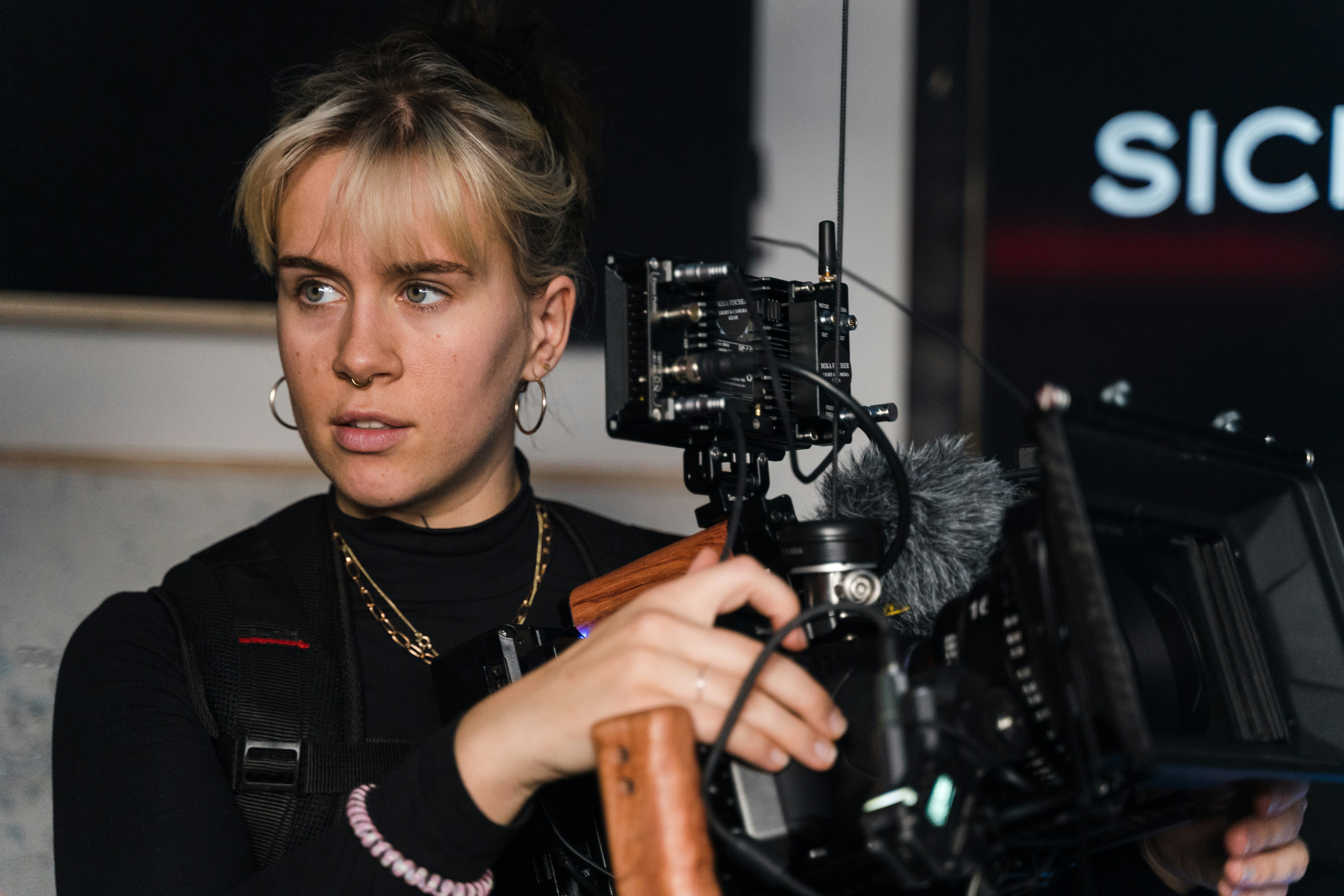 a woman holding a camera in front of a sign