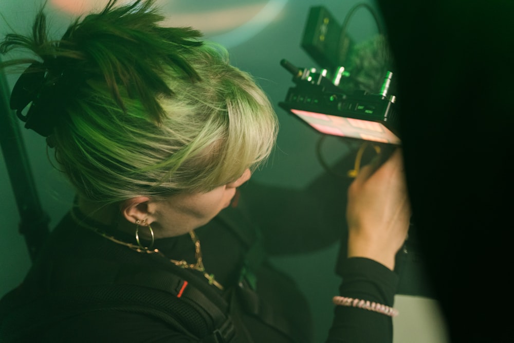 a woman with green hair is holding a radio