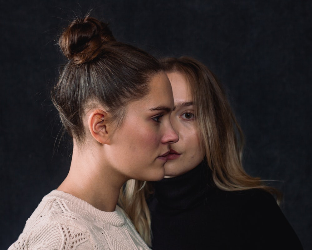 two women standing next to each other in front of a black background