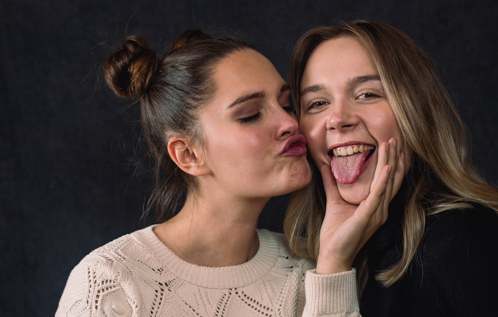 two women with their mouths open, one of them is licking the other's