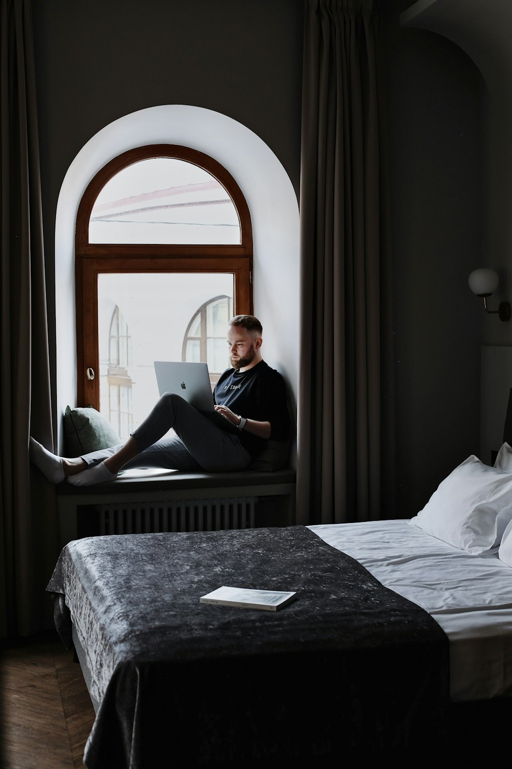 a man sitting on a bed using a laptop computer